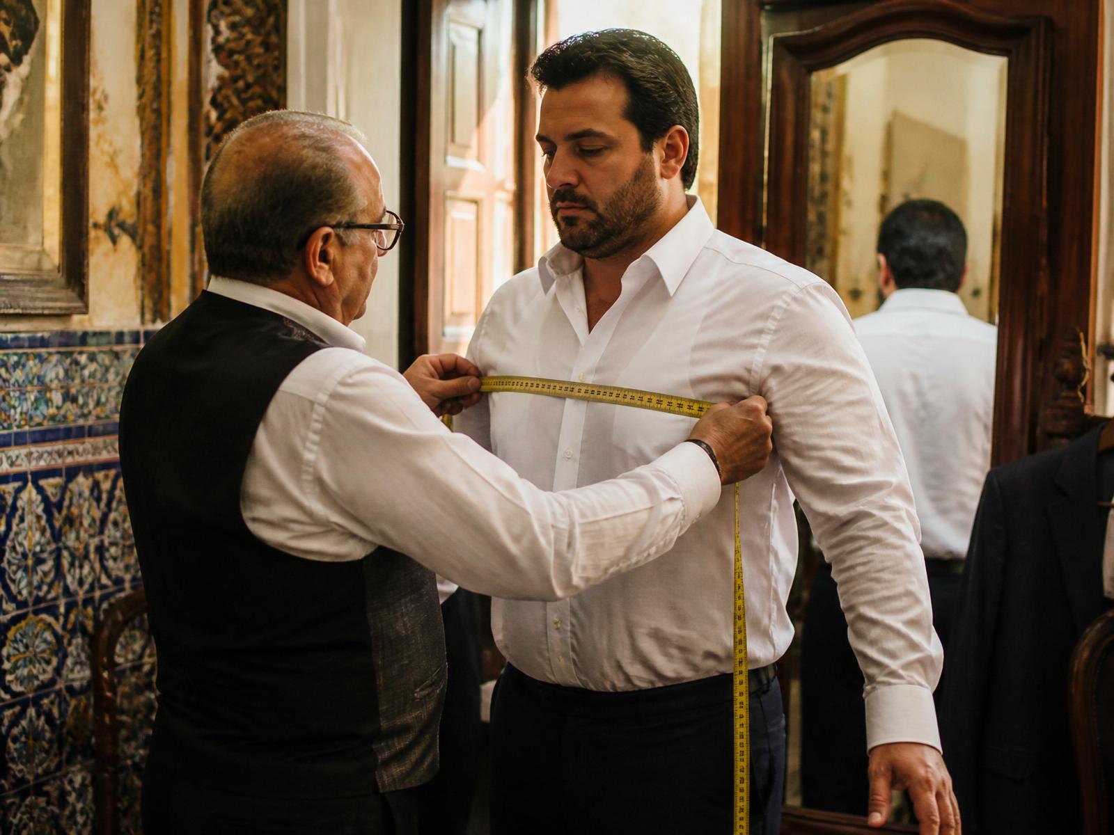 Sastre midiendo los hombros de un cliente de talla grande en un atelier sevillano
